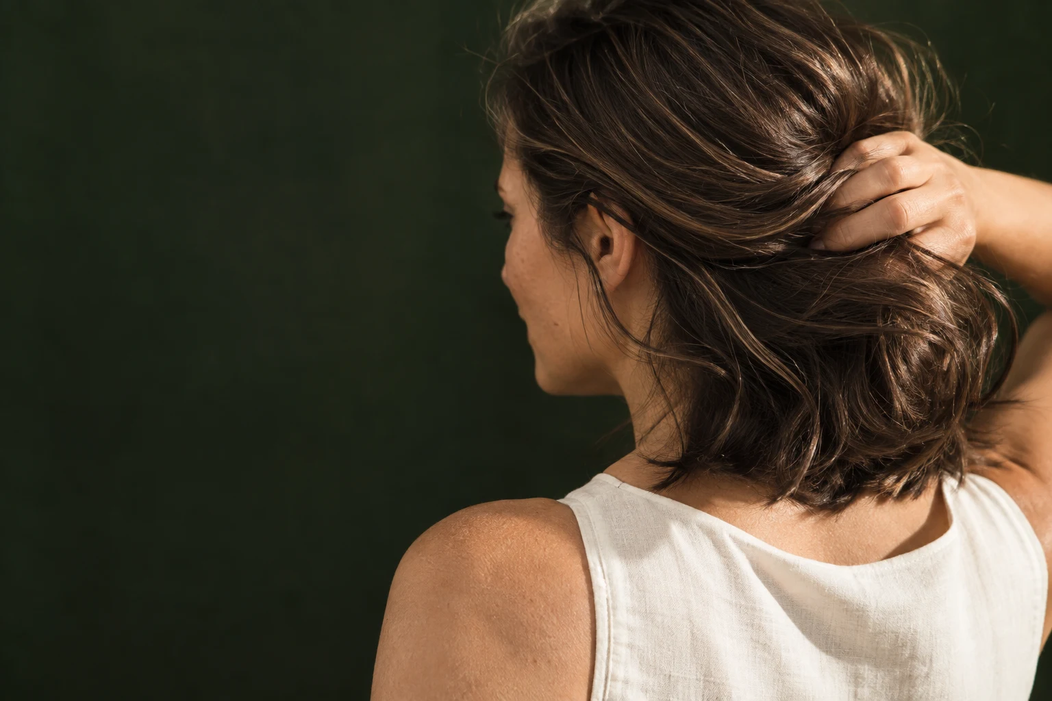 Woman gently lifting her natural brown hair